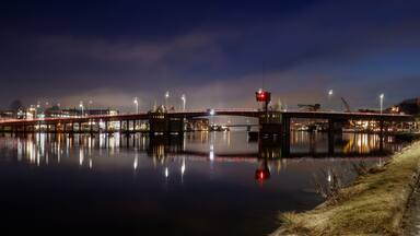 Northern industrial heritage spirit- illuminated lift bridge spanning river in Porsgrunn Norway with mirrored lights emphasizing Scandinavian infrastructure and regional transformation.