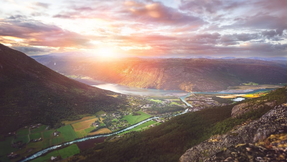 A valley with a river, mountains, and a small settlement.