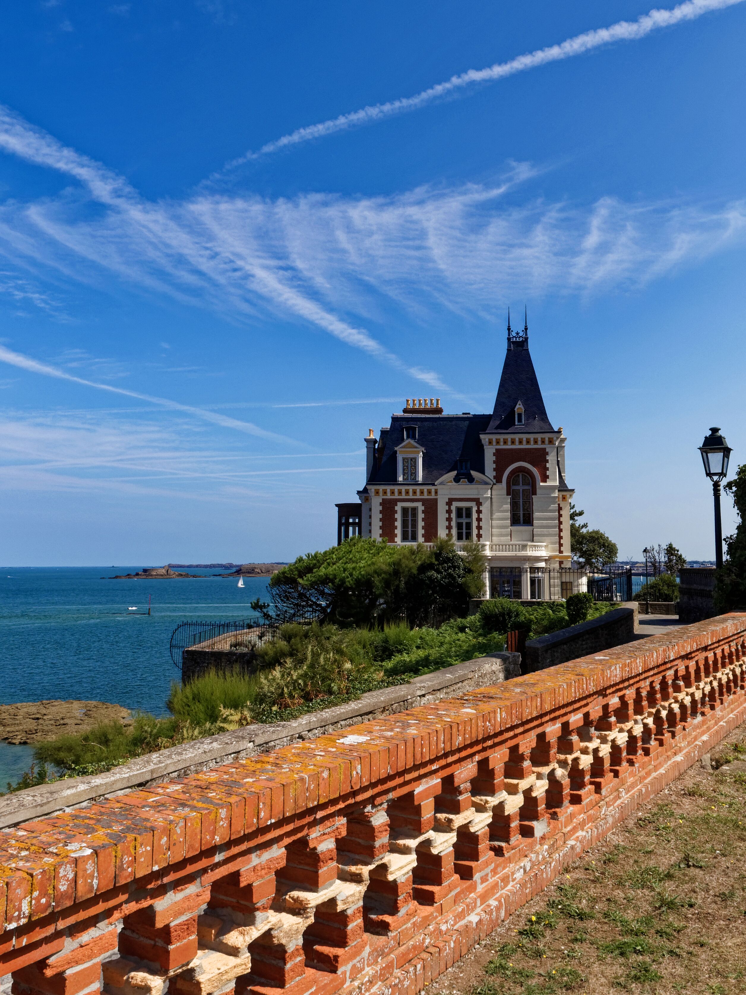 A coastal building with a prominent tower, a brick wall, and a clear blue sky.