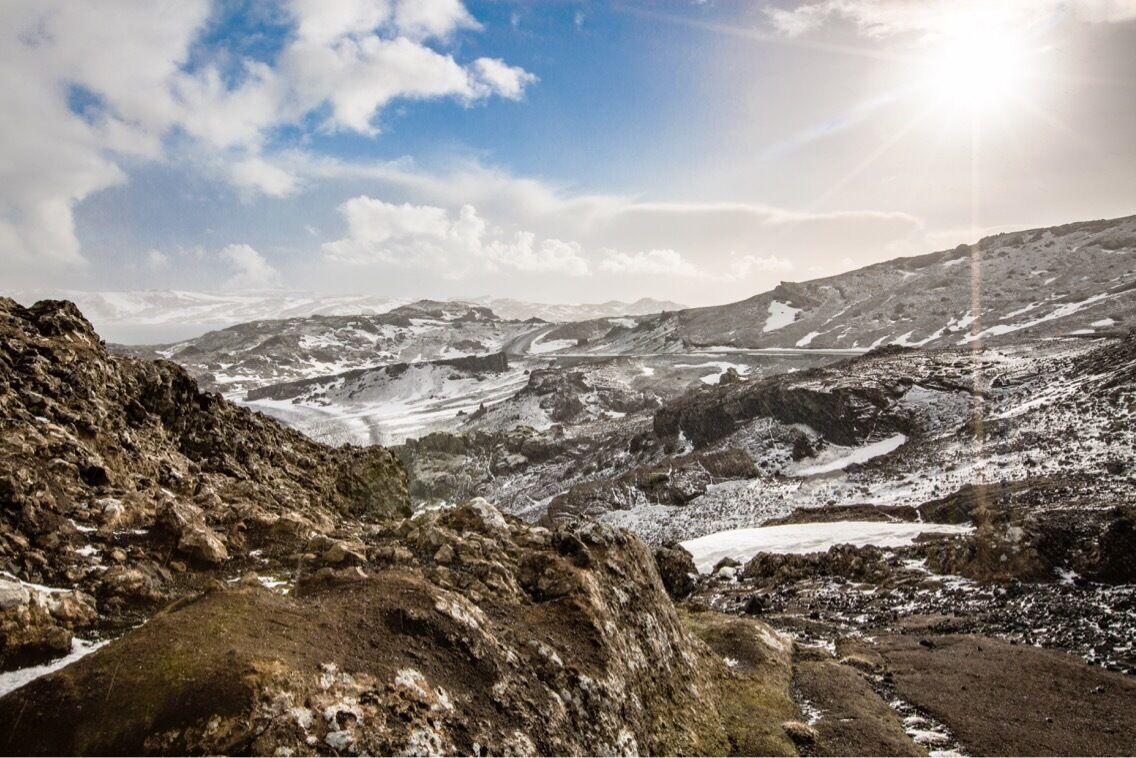 A rugged mountainous landscape with snow patches and a winding path.