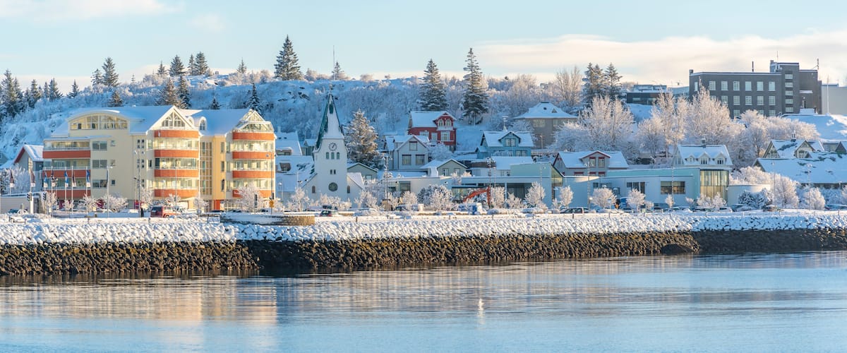 A snow-covered town with a river, buildings, and a church.