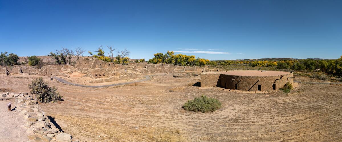 An archaeological site with ancient ruins, a circular structure, and sparse vegetation.