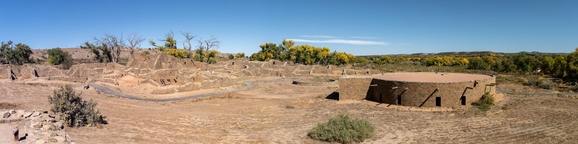 An archaeological site with ancient ruins, a circular structure, and sparse vegetation.