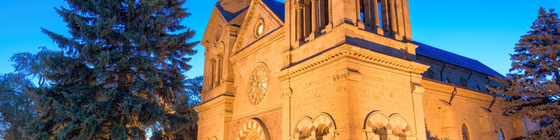 Una iglesia grande e histórica, con una destacada torre de reloj y ventanas en arco.