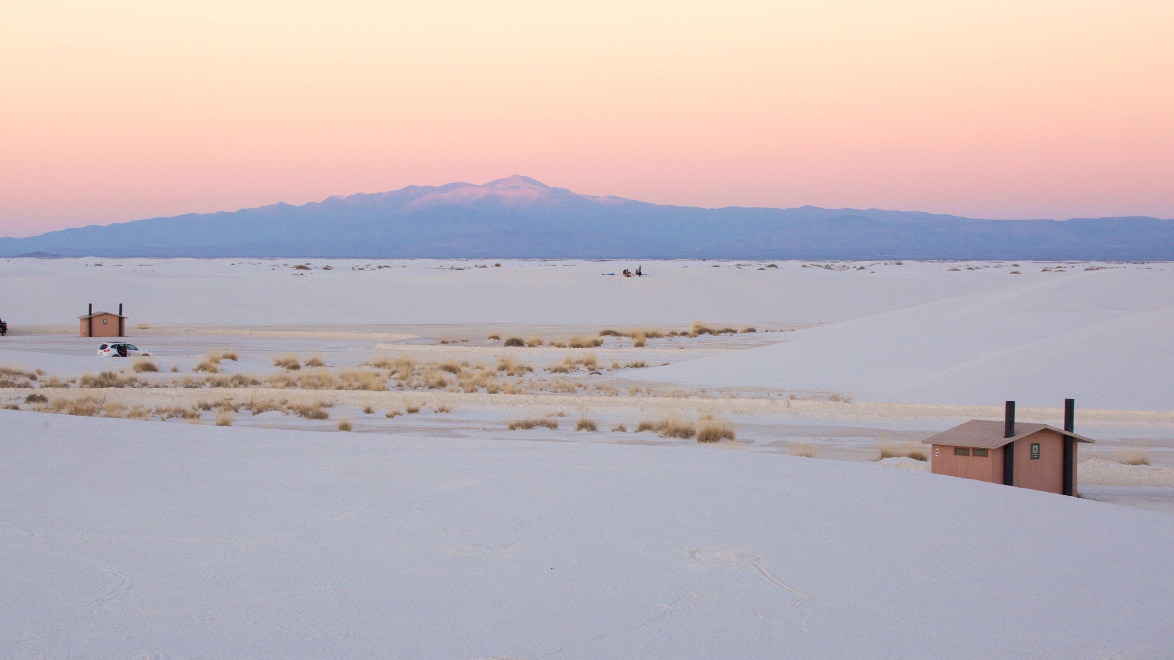 A snowy landscape with a small building and a distant mountain range.