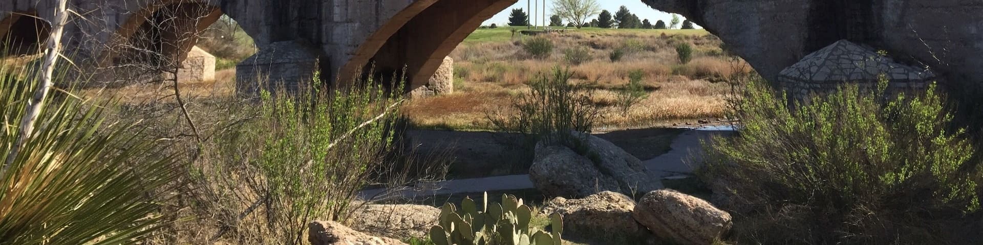 This irrigation flume continuously leaks water onto the roadway below as it ages gracefully since its 1929 completion. It replaced the original wooden structure built in the 1880s that eventually collapsed. A stone cottage was built adjacent to this spot for the water manager to live in while maintaining water levels for the farmers and citizens of Carlsbad.