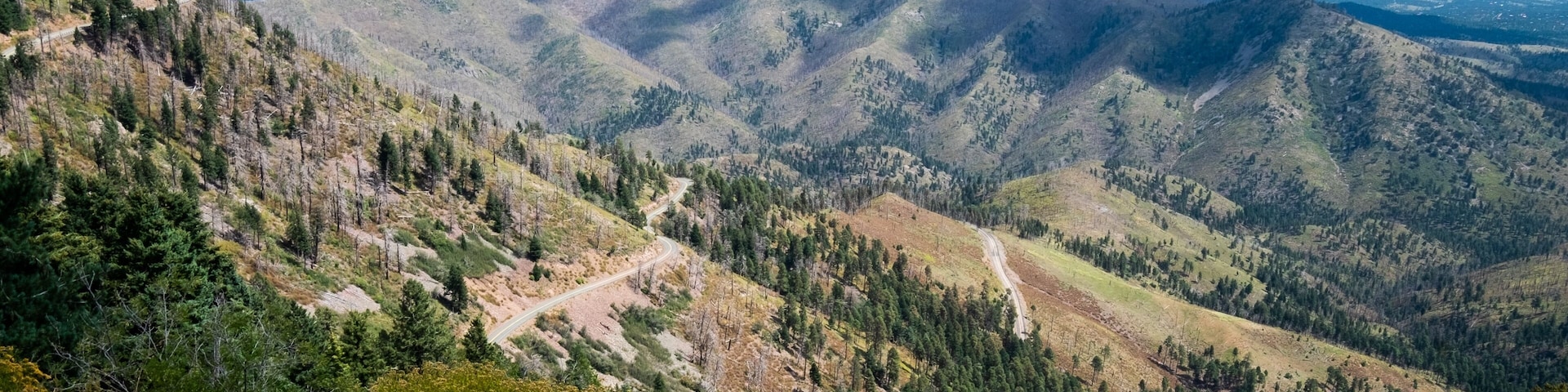 A mountainous landscape with winding roads and dense forests.