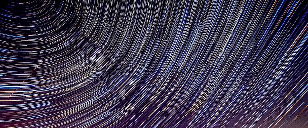 A star trail photograph with a cityscape in the foreground.