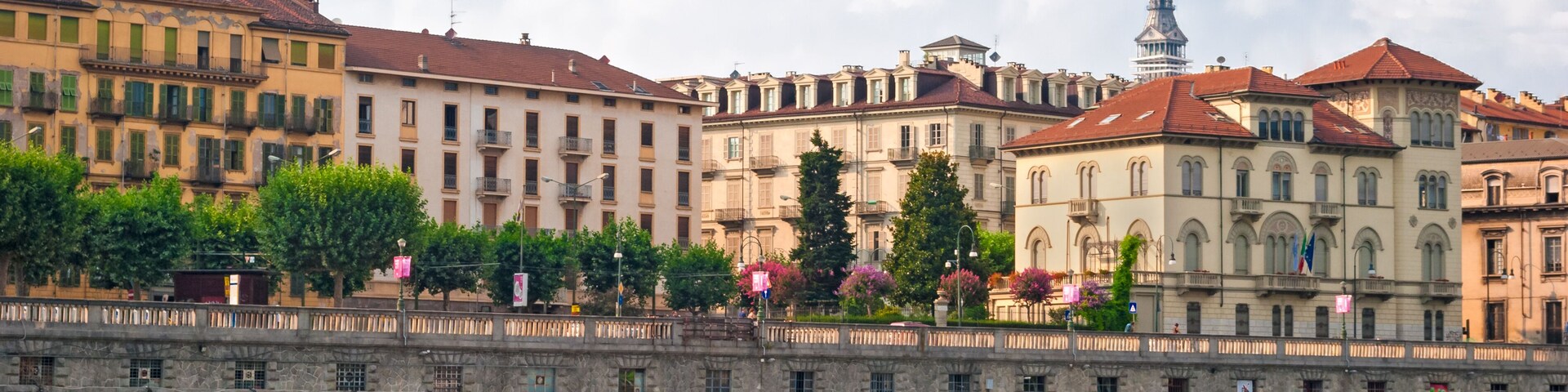 A riverside view with historic buildings, a prominent tower, and outdoor cafes.