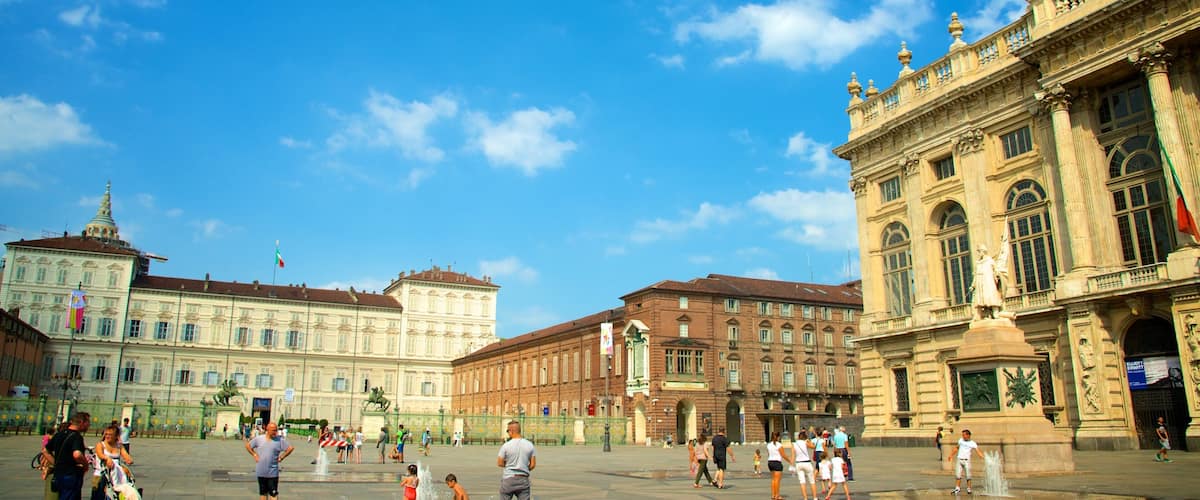 A public square with historic buildings, fountains, and people.