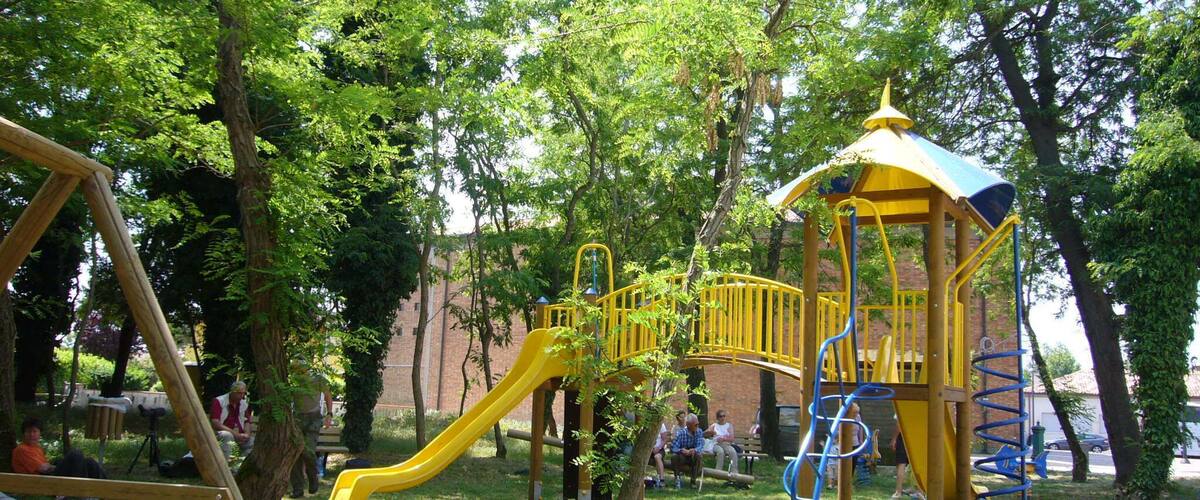 A playground with a yellow slide, a swing set, and a covered playhouse.