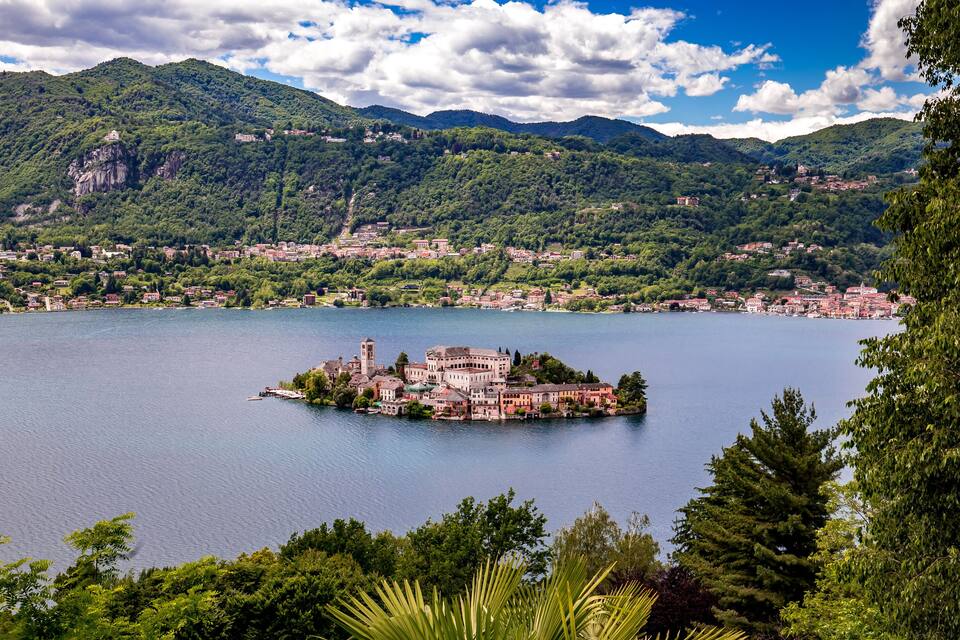 Un lago circondato da montagne e una piccola isola con edifici.