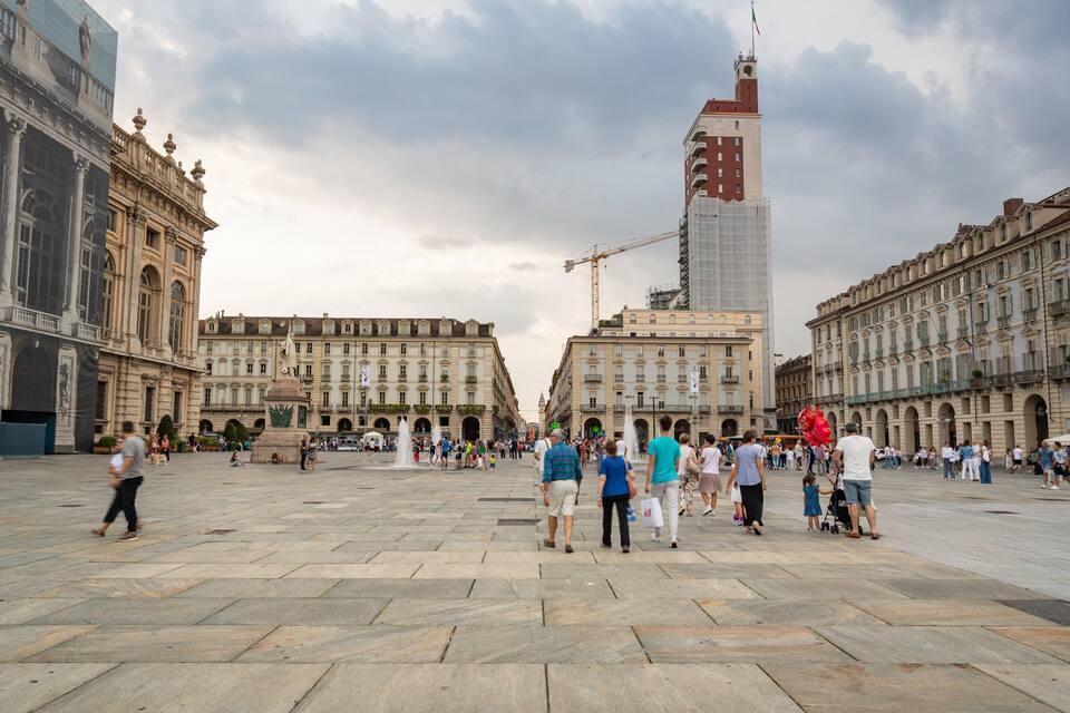 Una piazza vivace con edifici storici, un'imponente torre e una fontana.