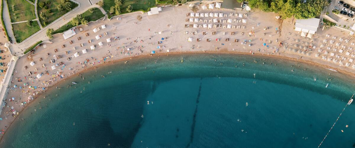 An aerial view of a beach with numerous umbrellas and sun loungers.
