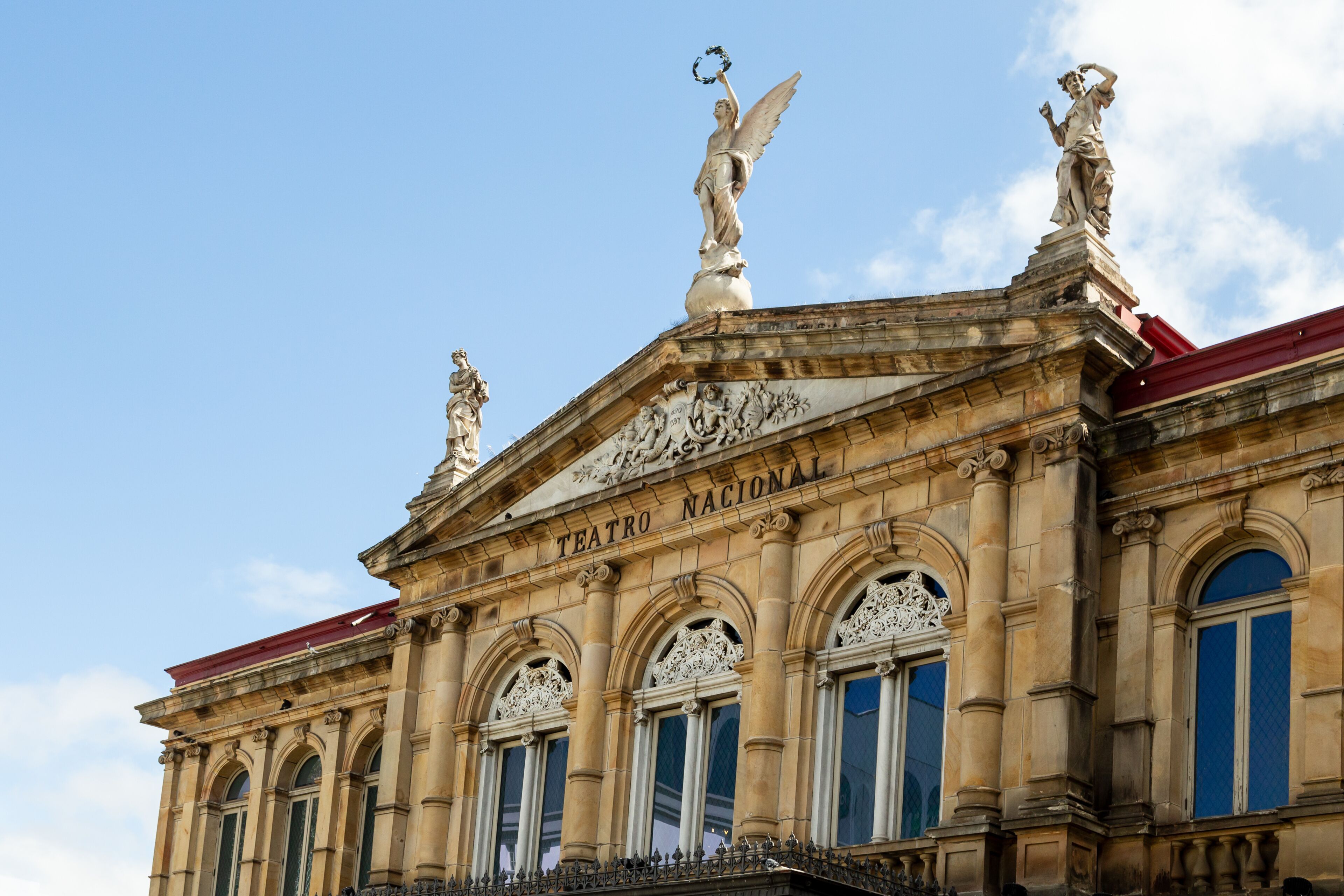 Low angle view of the 1897 National Theatre’s top story, with its magnificent neo-classical architecture and statues, San Jose, Costa Rica
