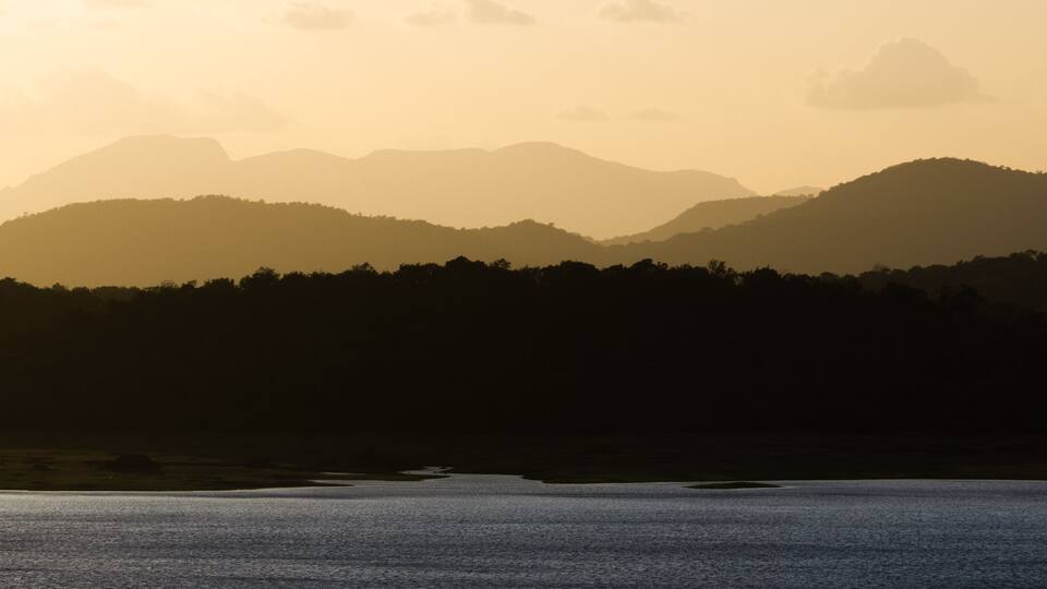 A mountain range at sunset with a lake in the foreground.