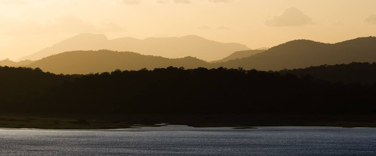 A mountain range at sunset with a lake in the foreground.