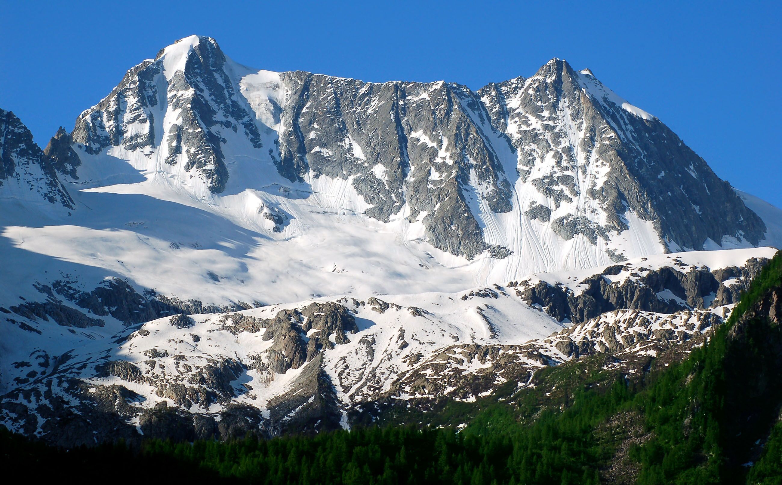 A snow-covered mountain with sharp peaks and rocky terrain.