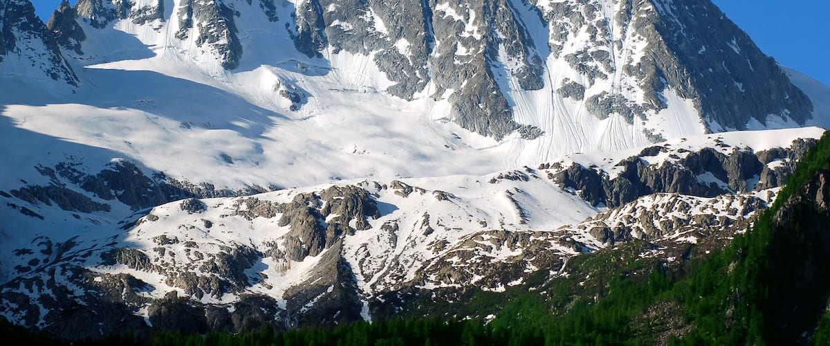 A snow-covered mountain with sharp peaks and rocky terrain.