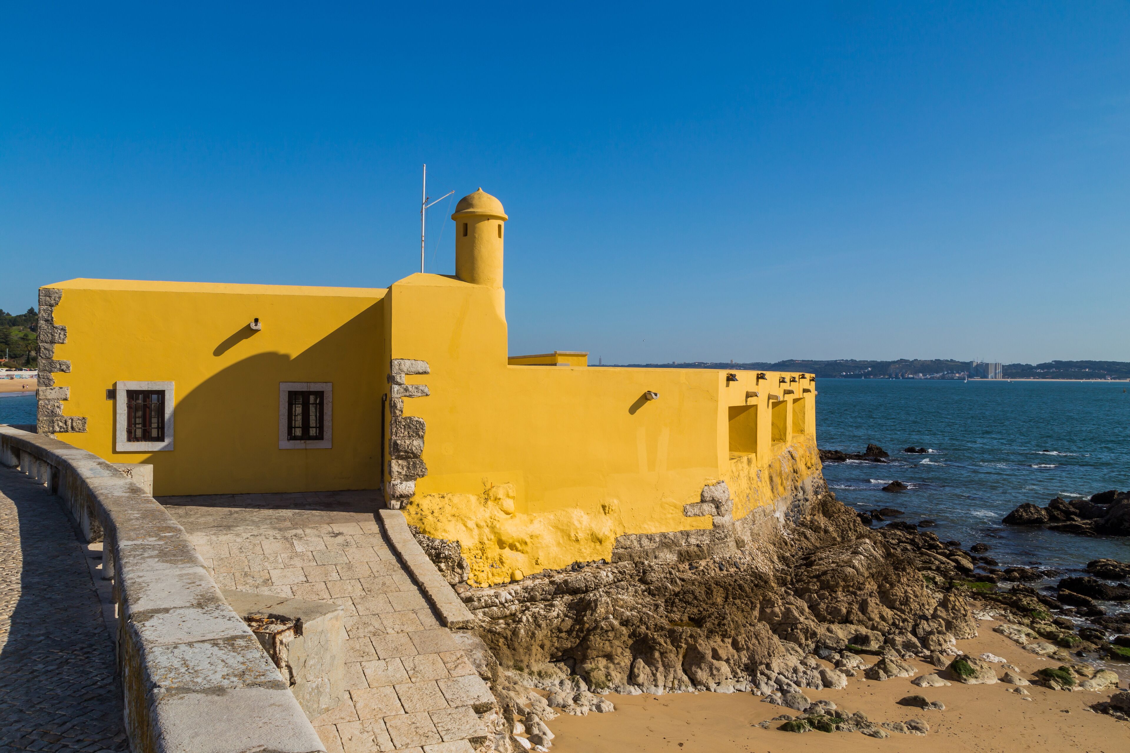 A yellow building with a tower by the sea.
