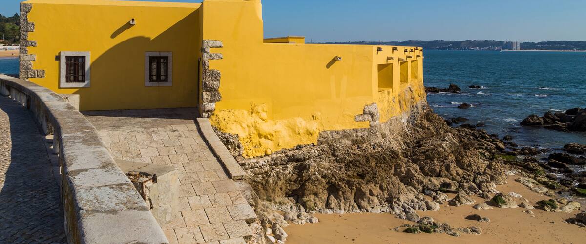 A yellow building with a tower by the sea.