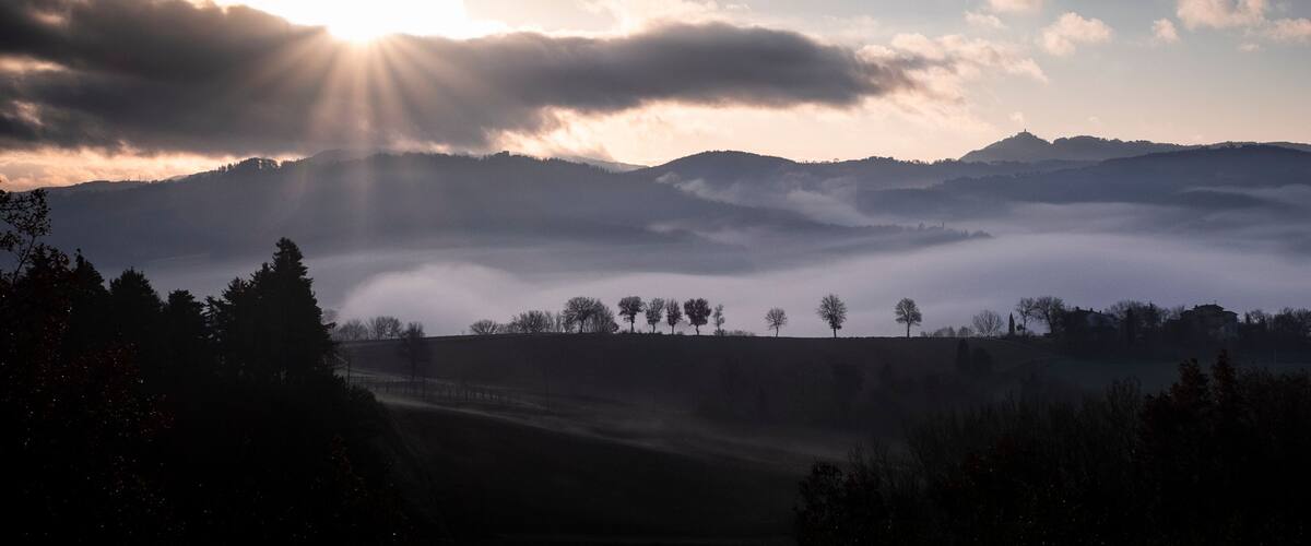 A misty mountain landscape with a sunlit sky.