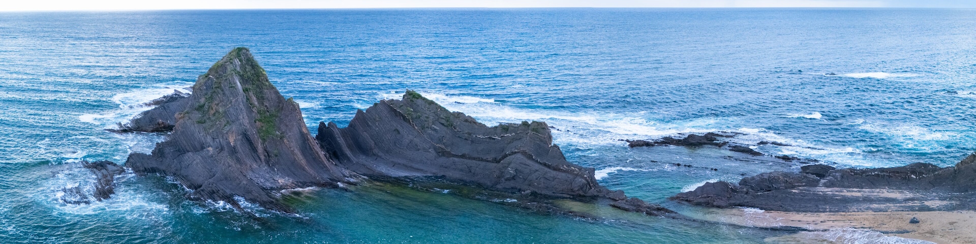 Eine Küstenlandschaft mit markanten Felsformationen und klarem, türkisfarbenem Wasser.