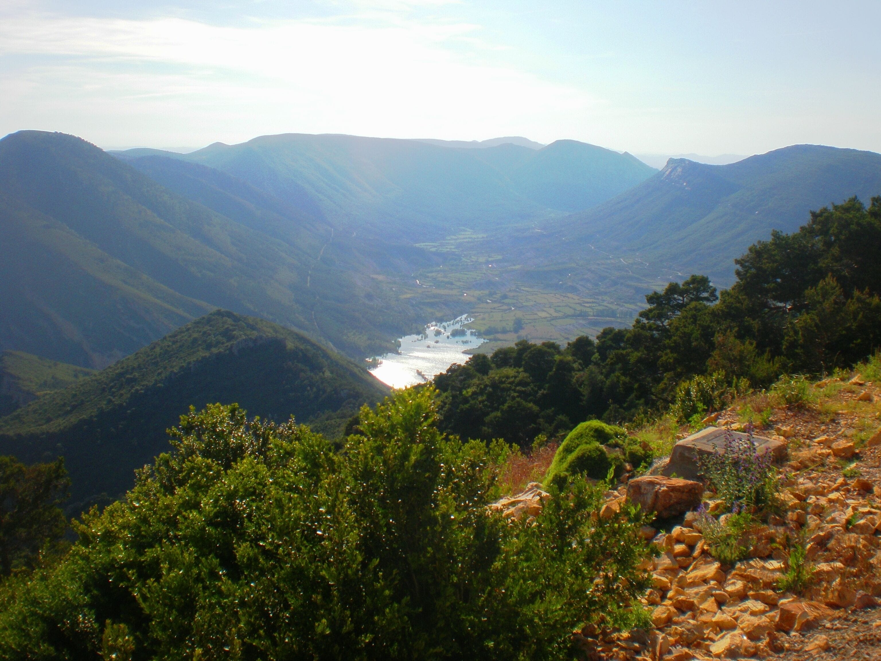 Un valle con un río, rodeado de montañas y vegetación densa.