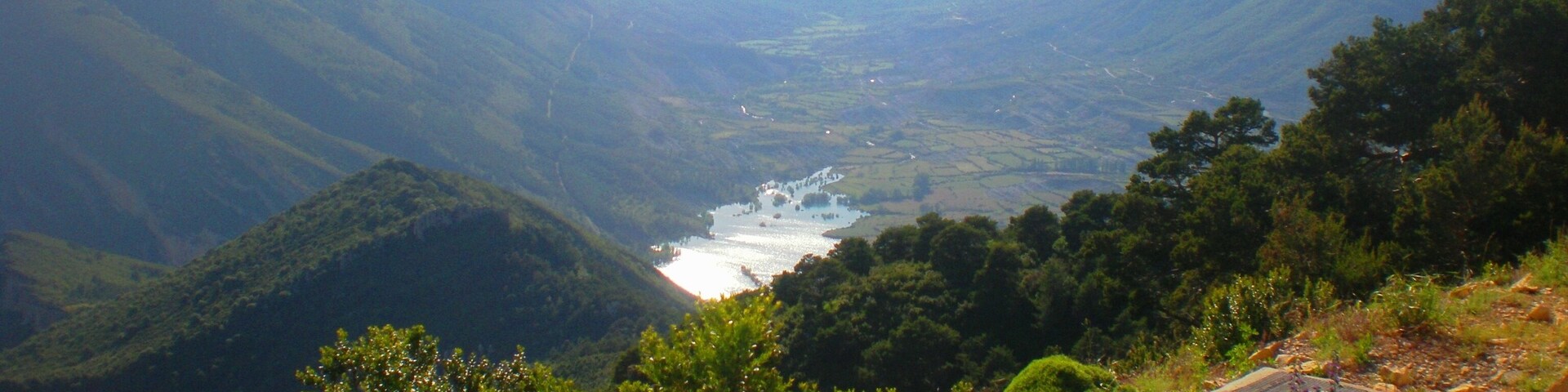 Un valle con un río, rodeado de montañas y vegetación densa.