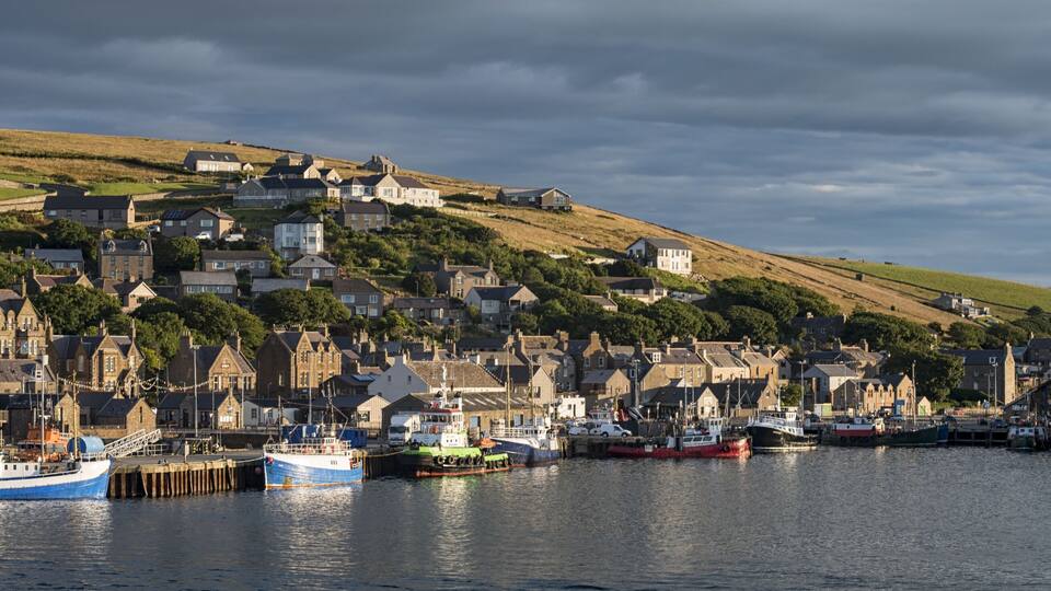 A coastal town with a harbor, boats, and houses on a hillside.