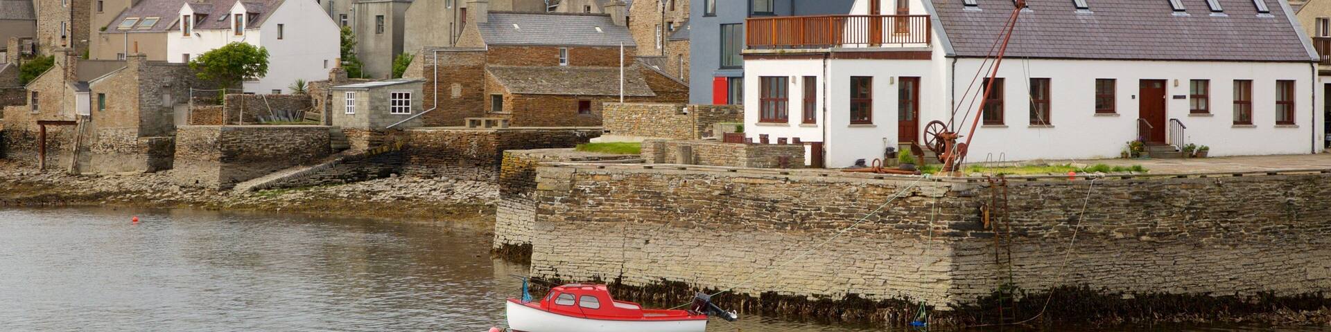 A coastal town with stone buildings and a red boat in the water.