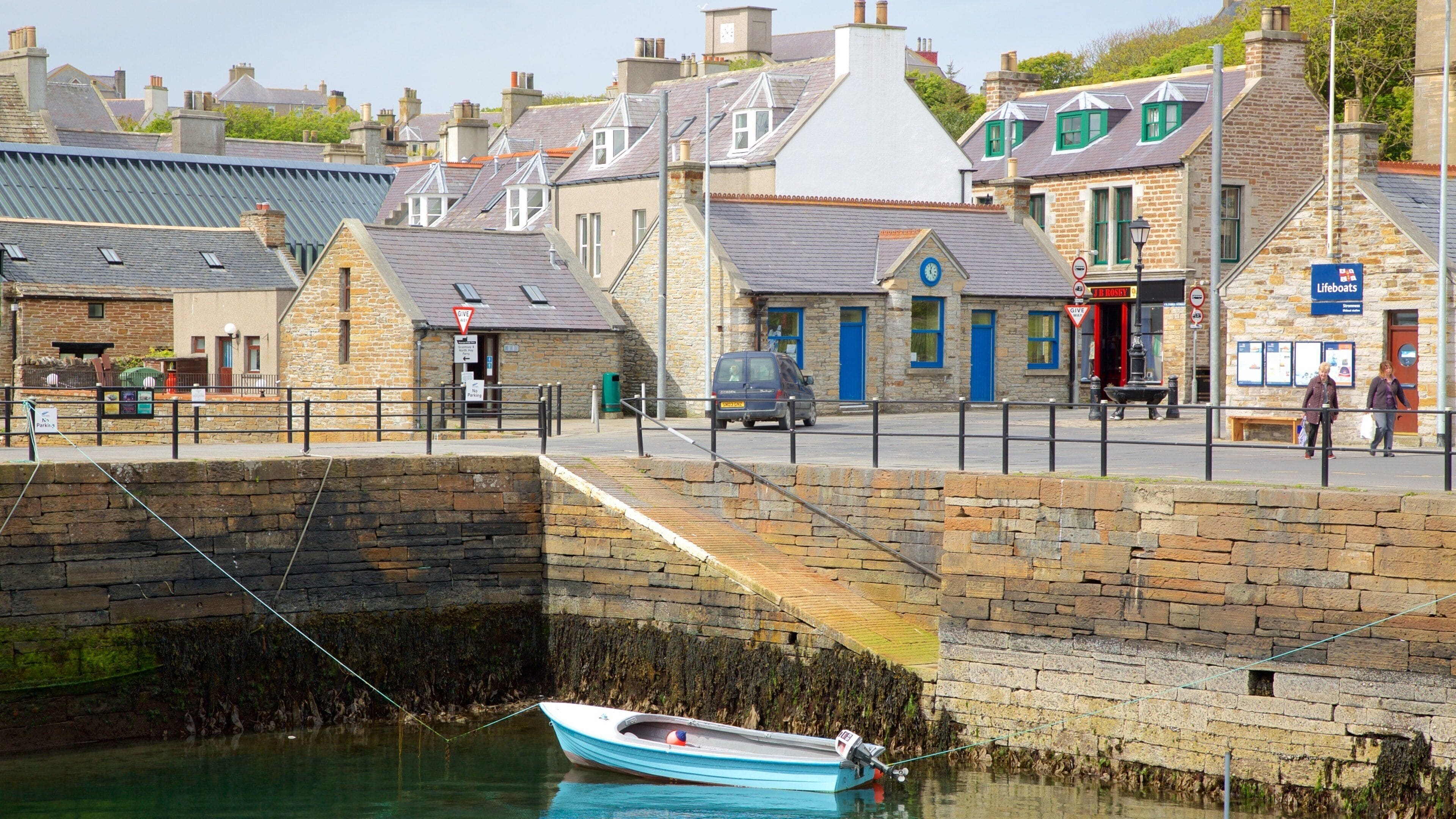 A coastal town with stone buildings, a lifeboat station, and a moored boat.