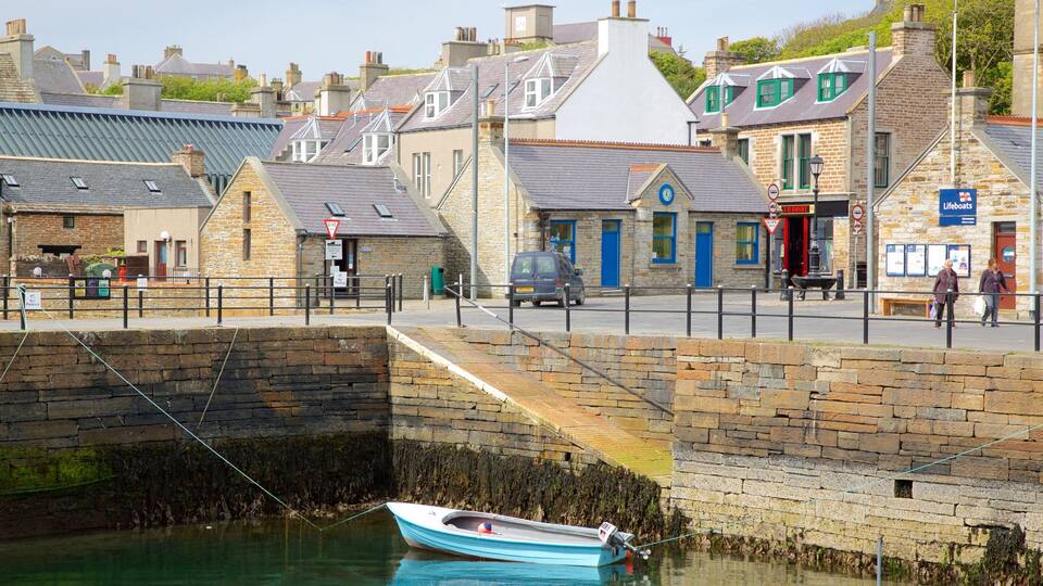 A coastal town with stone buildings, a lifeboat station, and a moored boat.
