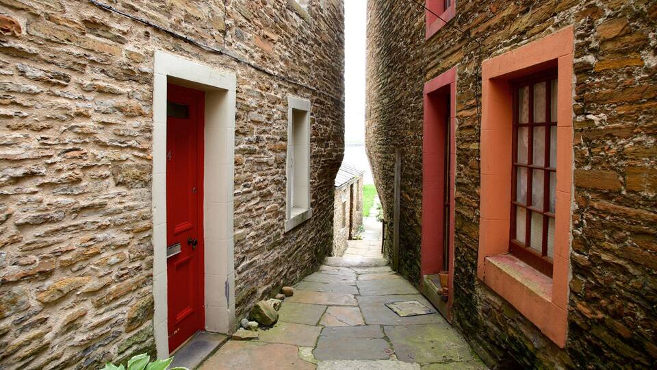 A narrow stone alleyway with red doors and windows.