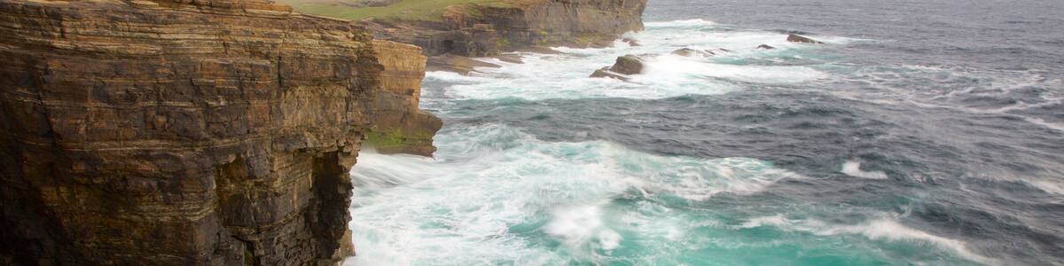 Une côte accidentée, avec de hautes falaises et des vagues océaniques déchaînées.
