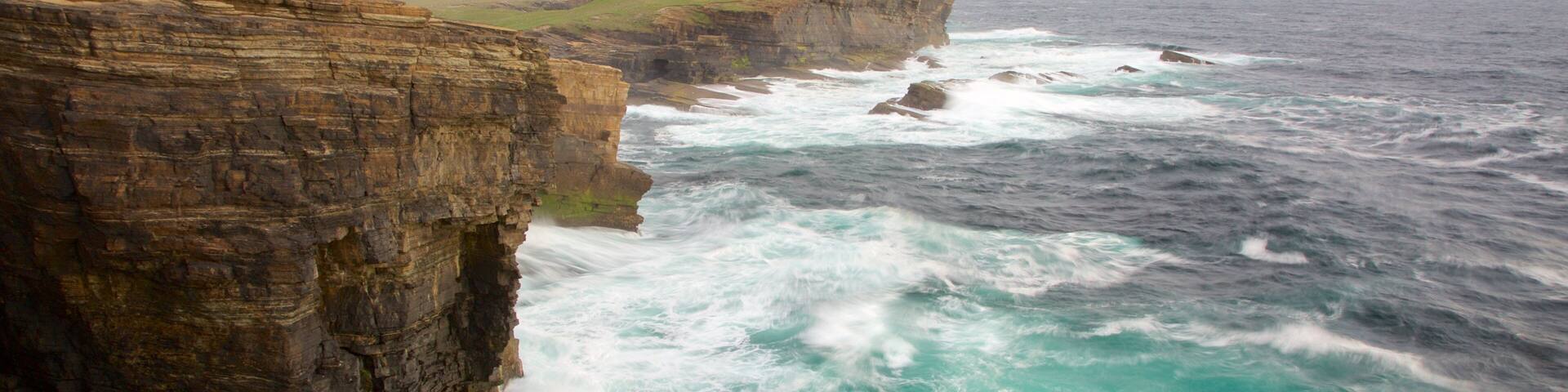 A rugged coastline with steep cliffs and turbulent ocean waves.
