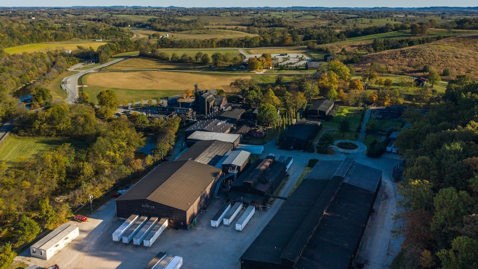 An industrial area with warehouses, a road, and surrounding green fields.
