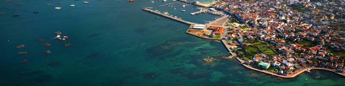 An aerial view of a coastal town with a marina, clear blue waters, and surrounding islands.