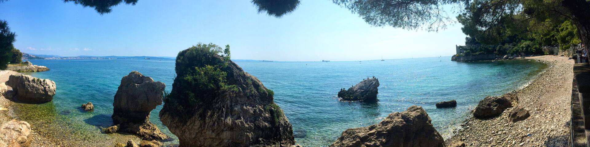 A coastal landscape with rocky outcrops and clear blue sea.