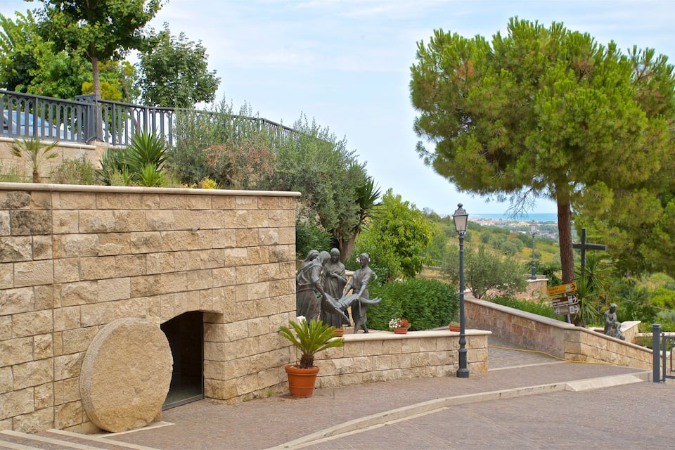 A stone wall with a statue, a stone archway, and a view of the sea.