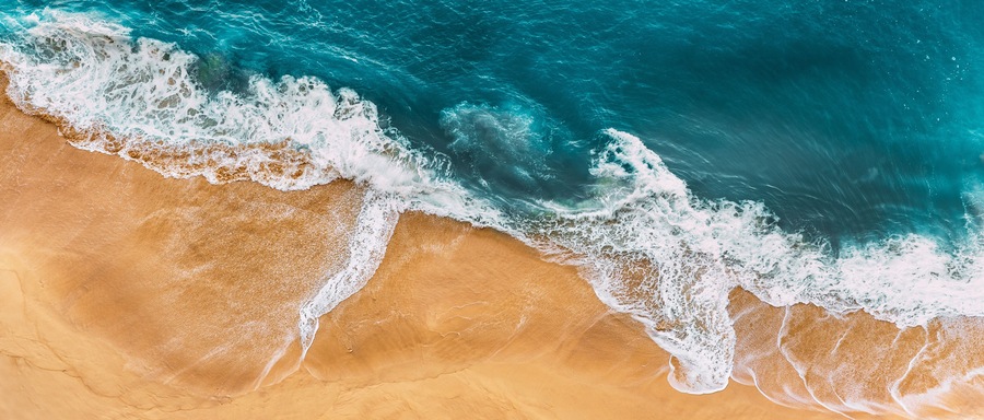 Una playa arenosa con olas rompiendo sobre la orilla.