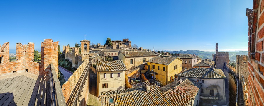 Paesaggio urbano storico con architettura medievale, che include un castello imponente e mura fortificate.