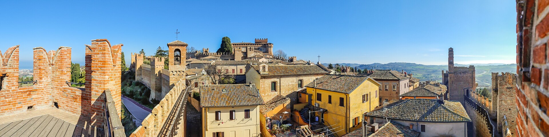 Un paisaje urbano histórico con arquitectura medieval, incluyendo un castillo destacado y murallas fortificadas.