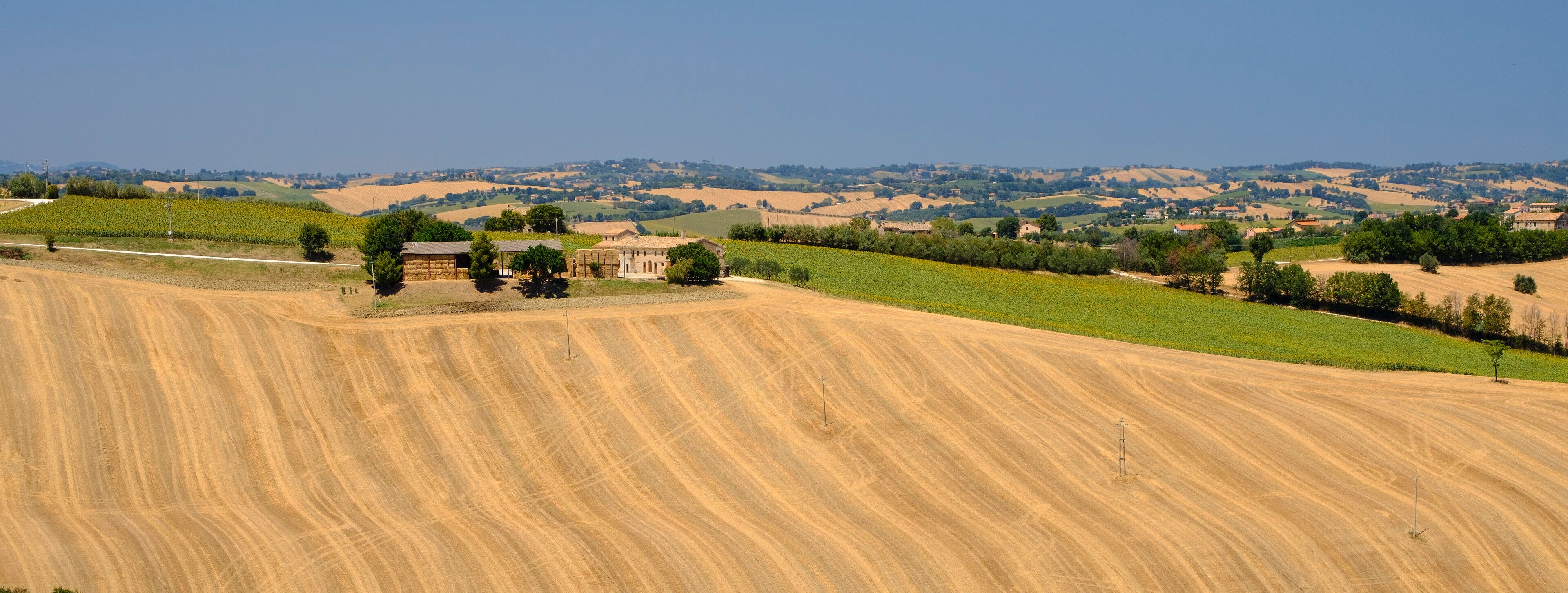 A rural landscape with rolling hills, agricultural fields, and scattered buildings.
