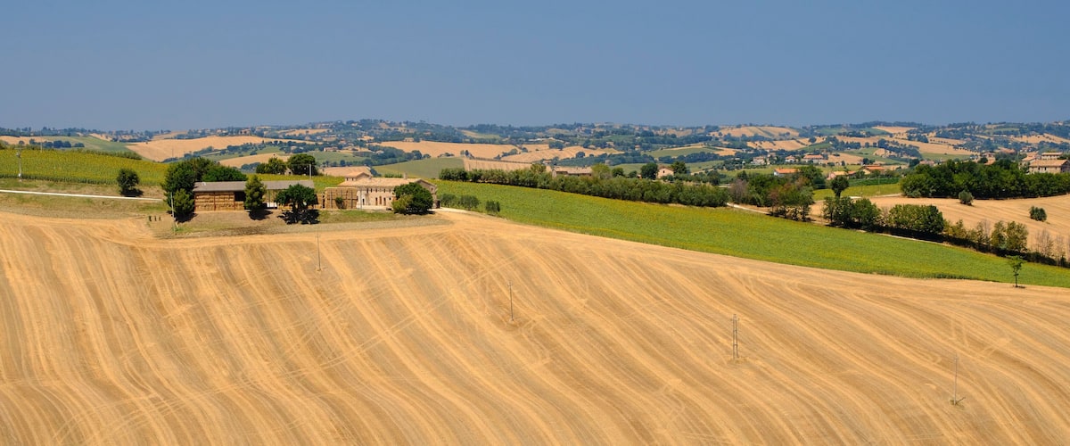 A rural landscape with rolling hills, agricultural fields, and scattered buildings.