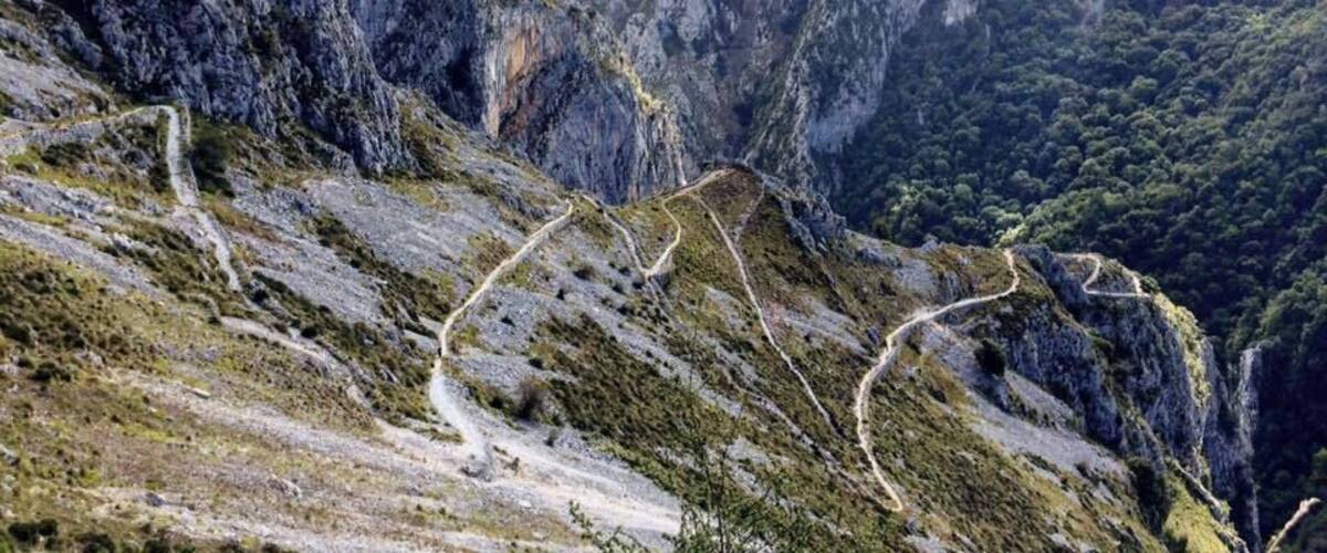 A winding mountain road surrounded by rugged terrain and steep cliffs.