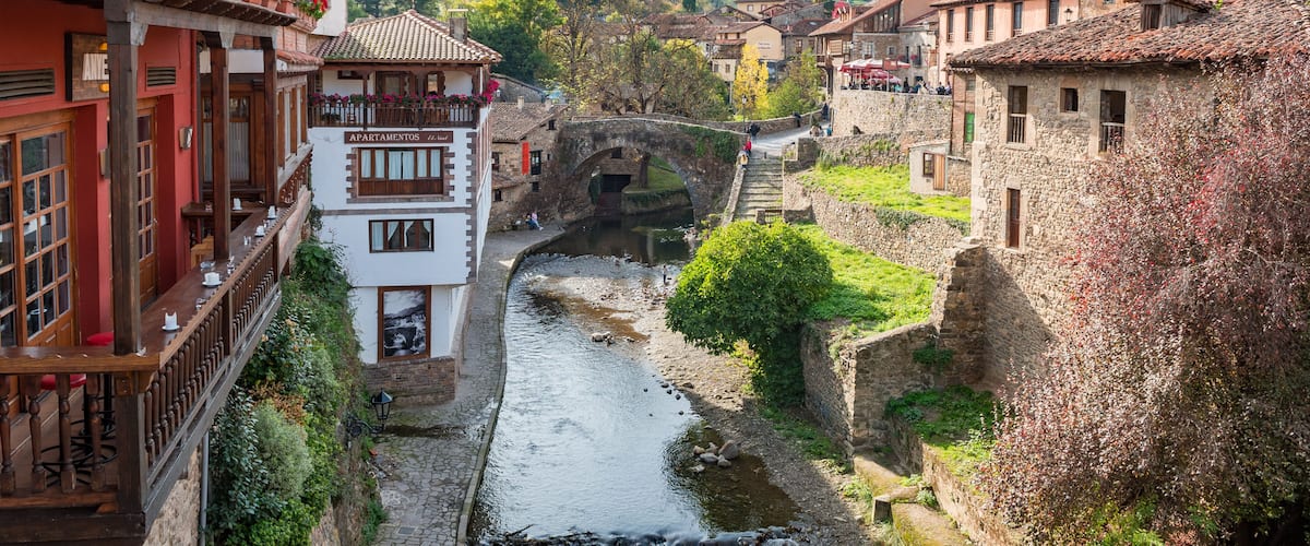 A river flowing through a historic town with stone buildings and a bridge.