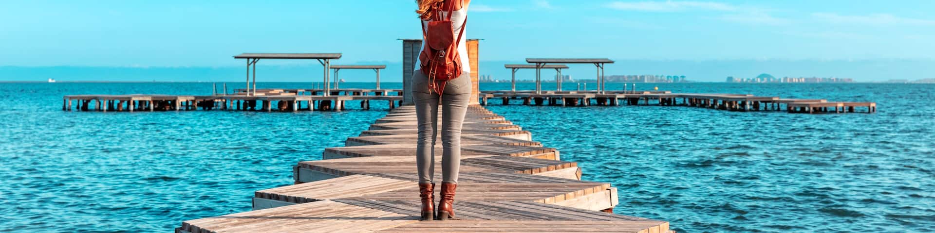 Happy woman standing on wooden pier above the sea ( santiago de la Ribera, Man Menor, Province Murcia in Spain)