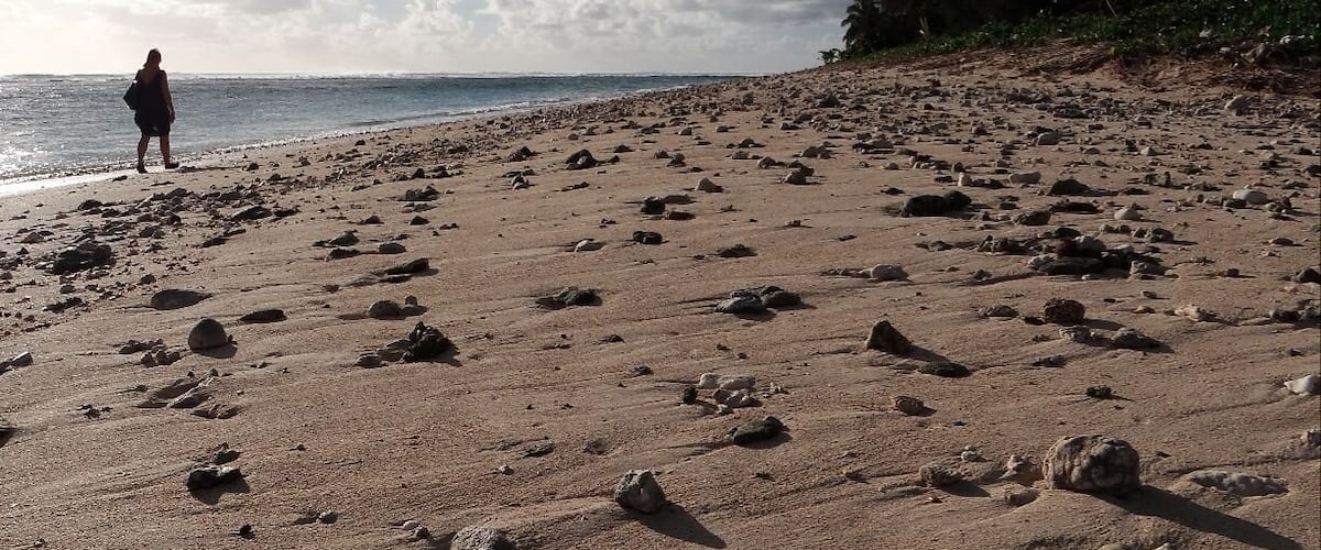 A rocky beach with footprints and a person walking towards the water.