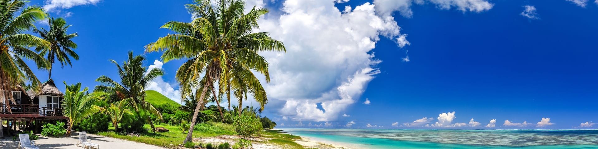 A tropical beach with palm trees, a wooden structure, and clear turquoise waters.